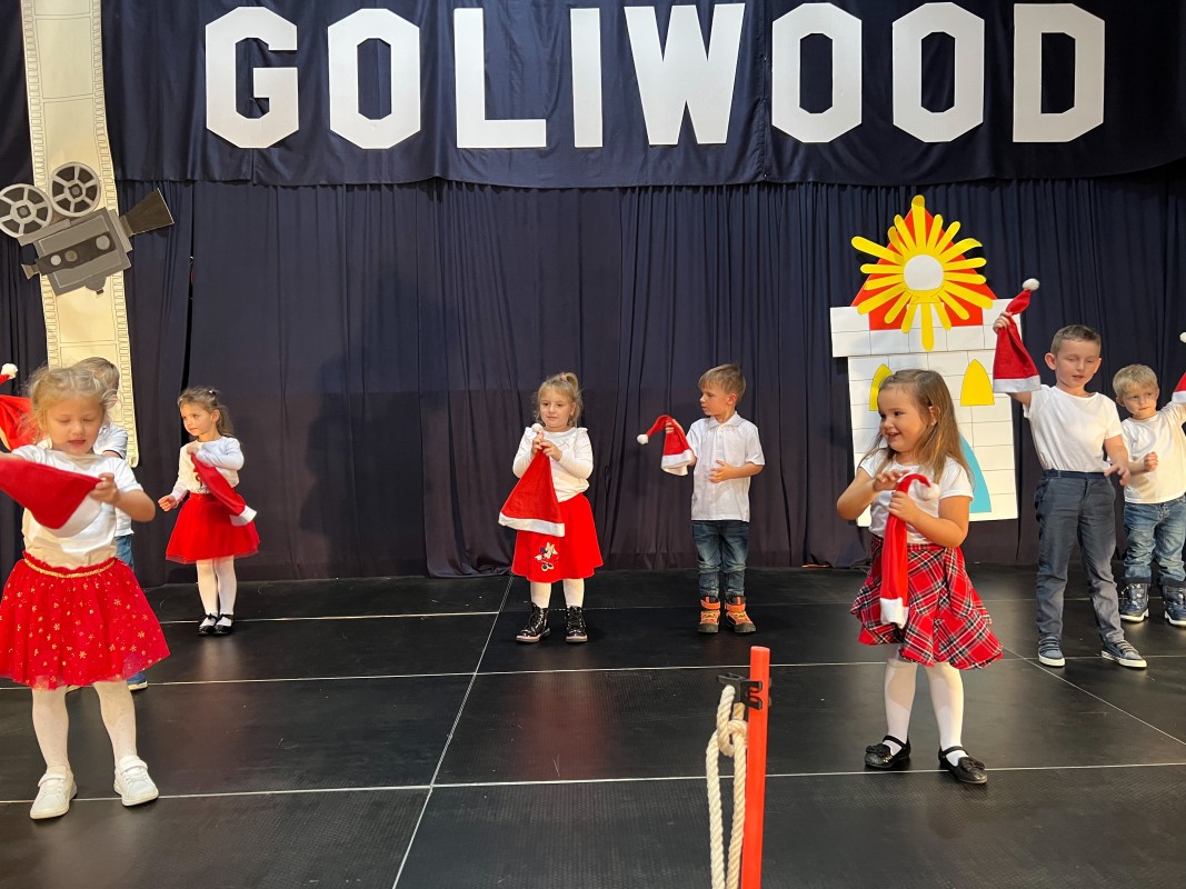 dzieci w strojach mikołajowych stoją na scenie podczas występu