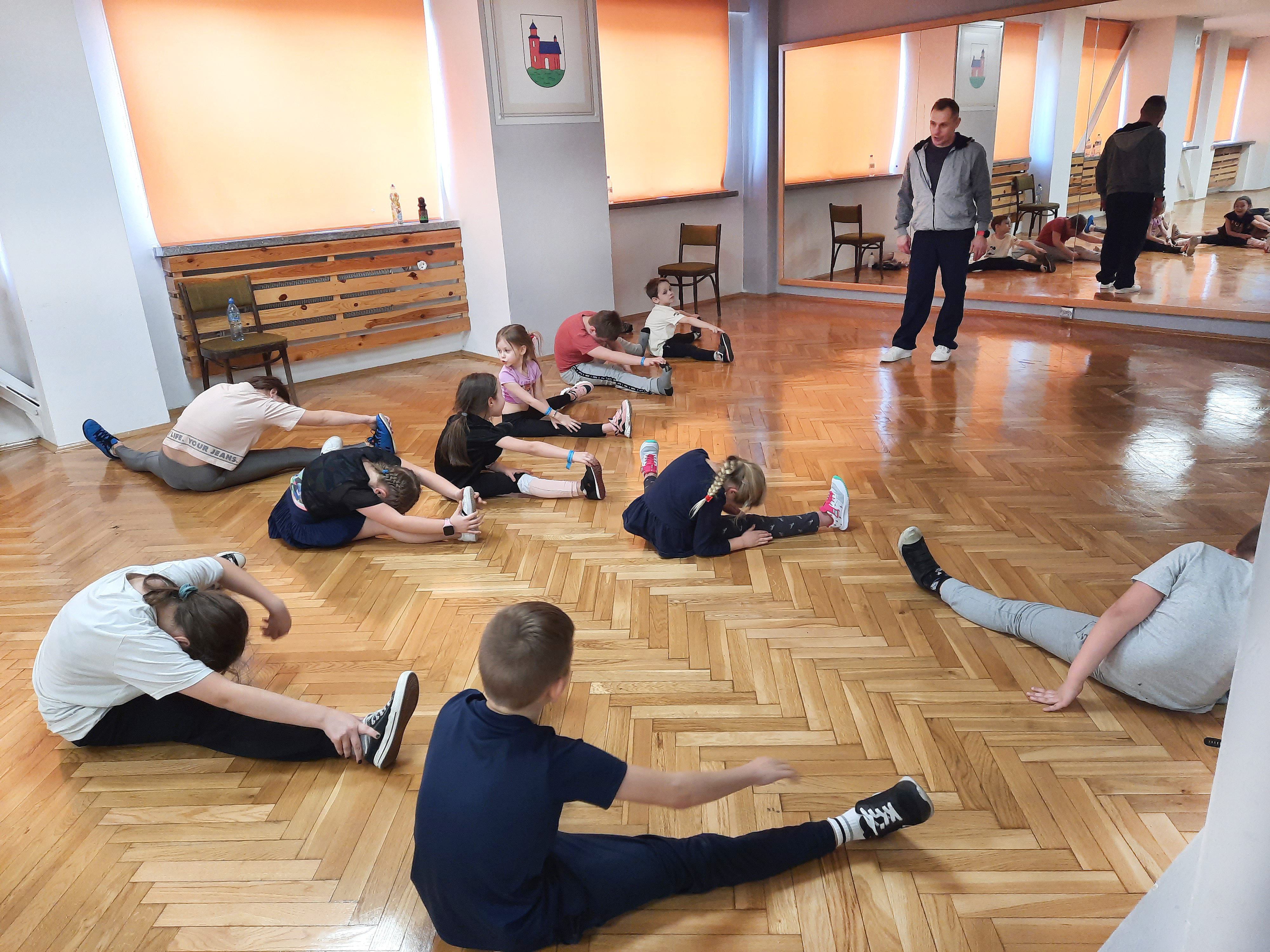 Dzieci podczas rozgrzewki przed zajęciami tańca - rozciąganie