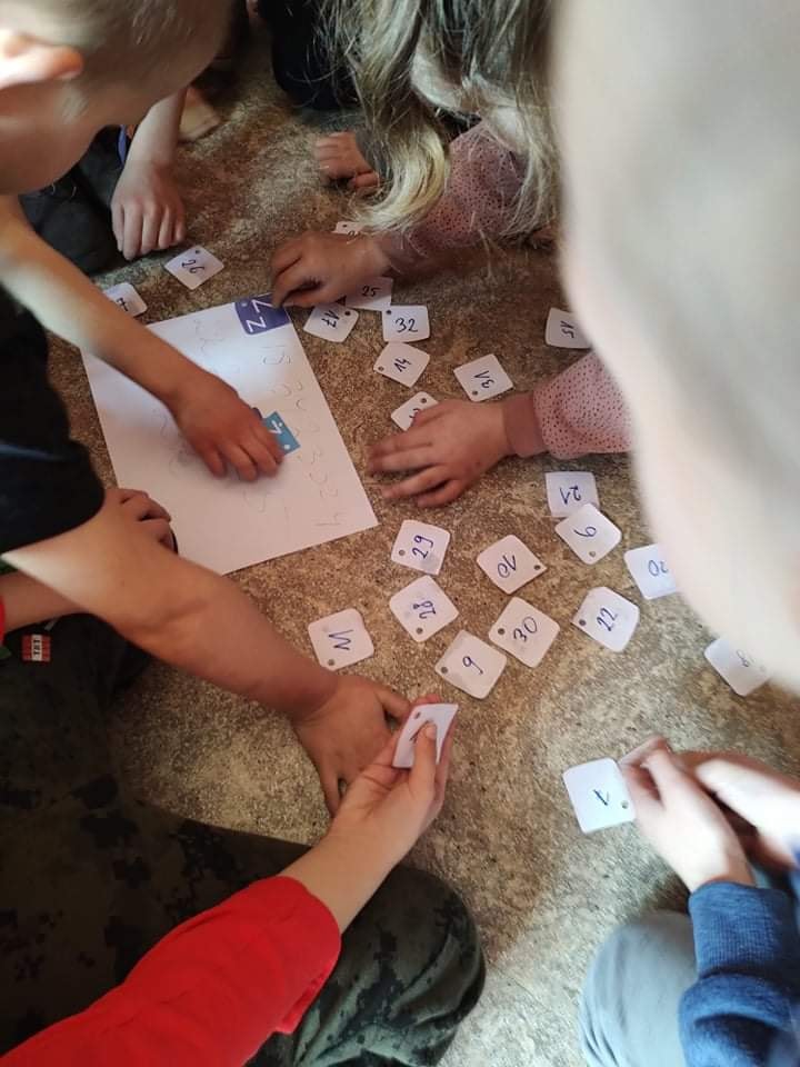 Ręce dzieci, na podłodze leżą karteczki z numerami