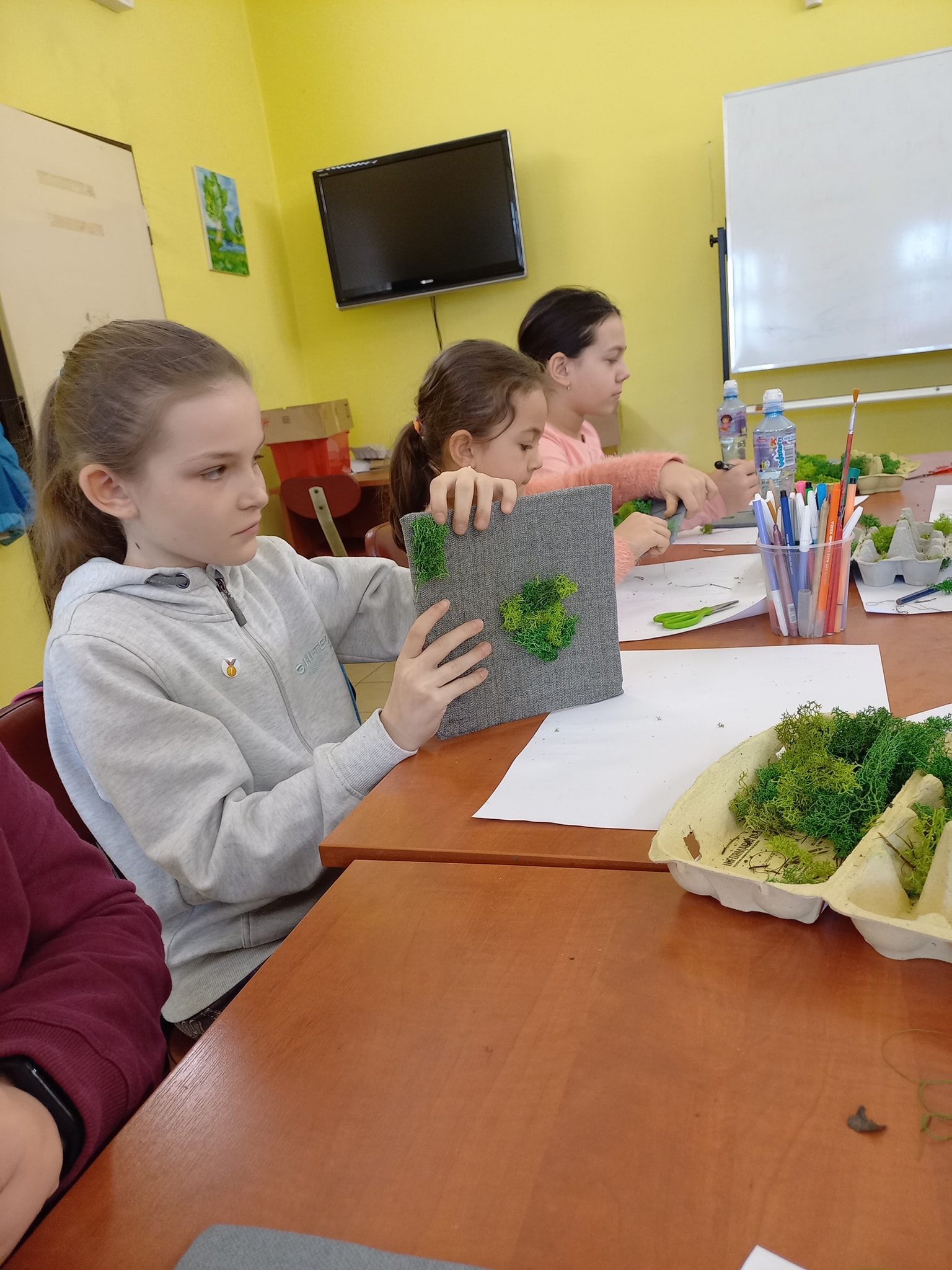 Dziewczynka przygotowuje pracę plastyczną z mchu