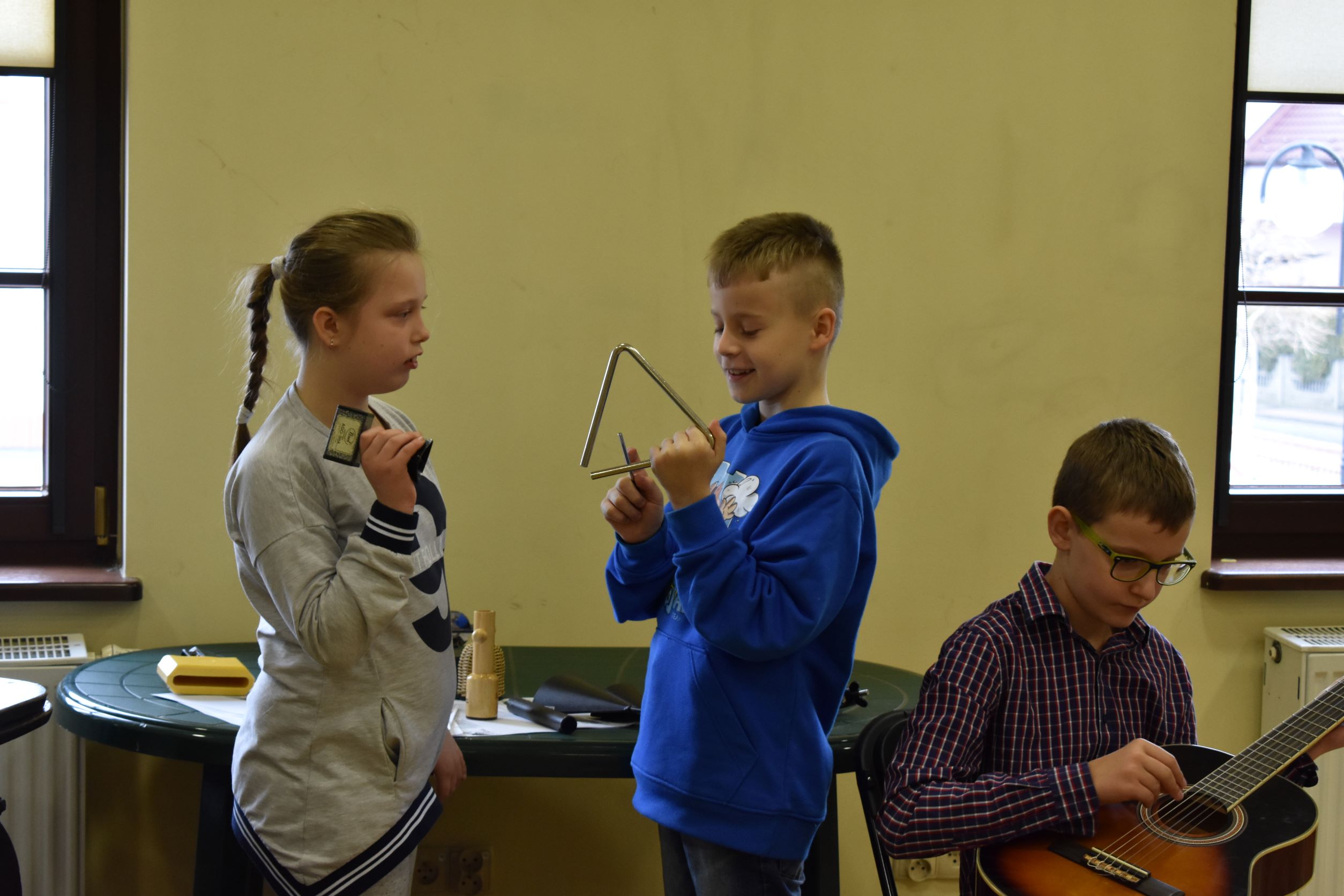 Dzieci podczas zajęć w bibliotece trzymają w rękach instrumenty muzyczne